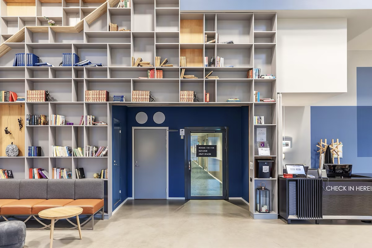 Residence lobby with a bookcase wall, seating, and a check-in desk